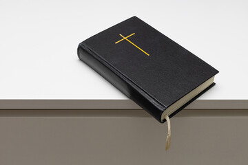 a closed bible with a cross on the cover lies on the table.