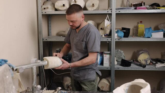 Mold creation, Prosthesis leg, Mold development. Hip disarticulation prosthesis mold being crafted by man who is eliminating all superfluous elements.