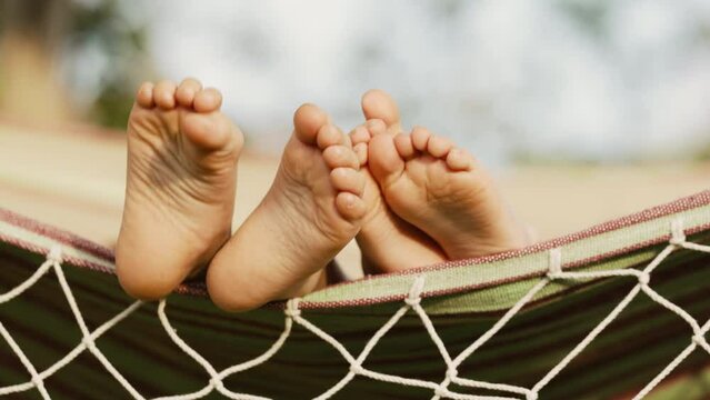 Feet of children, which swinging on hammock at summer.Kids relax,happy childhood