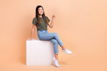 Full body size photo of young happy korean woman indicating finger empty space sitting podium...