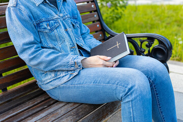 woman reading the bible sitting on a bench.