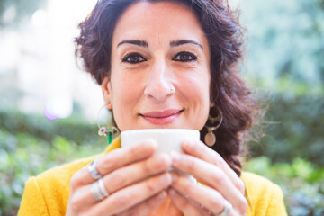Close-up of a woman looking at camera with a cup of coffee in her hand