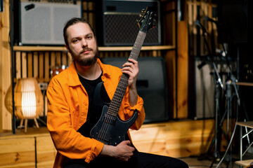 Obraz premium portrait of a rock performer with an electric guitar in a recording studio holds a musical instrument in his hands strings melody