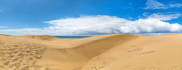 Dünen von Maspalomas auf der kanarischen Insel Gran Canaria, an der Küste des Atlantiks blauer Himmel und Wolken im Hintergrund, Panorama. - obrazy, fototapety, plakaty