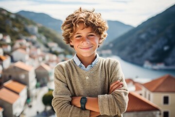 Lifestyle portrait photography of a joyful mature boy with crossed arms against a scenic cliffside village background. With generative AI technology