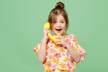 Little child kid girl 6-7 years old wearing casual clothes have fun talk speak on handset phone , isolated on plain pastel green background studio portrait. Mother's Day love family lifestyle concept.