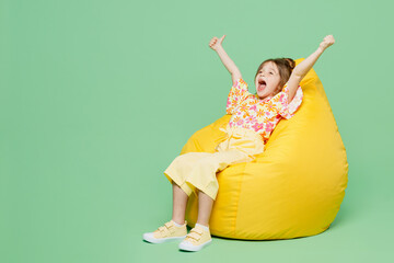 Full body excited winner little child kid girl 6-7 years old wears casual clothes sit in bag chair...