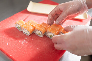 The chef prepares to serve sushi roll with salmon, cheese and cucumber