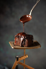 Piece of homemade chocolate cake on the vintage scales. Close up - 611049746
