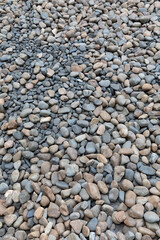 Pebbles or River stones background texture and color from modern garden. Vertical format
