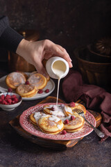 Female hand pouring liquid cream on fresh homemade pancakes with raspberries - 611050166