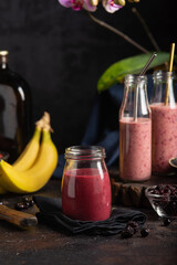 Berry-banana smoothie, berries and bananas still life in dark style. Close up - 611051142