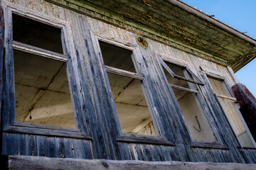Empty window openings at an old wooden abandoned landing stage on the banks of the Ob River in Siberia