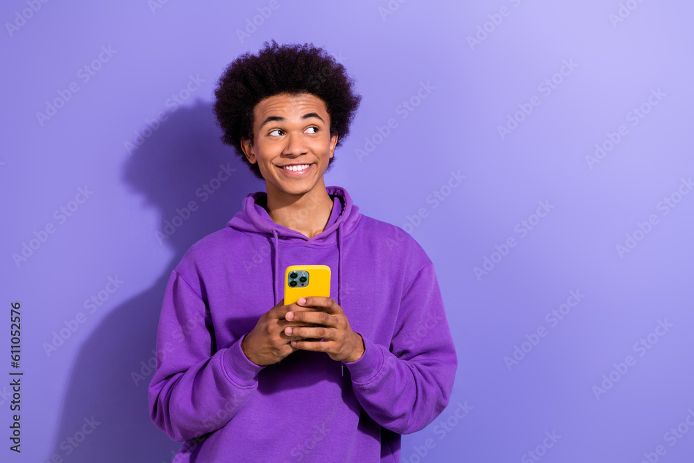 Wall mural Portrait of handsome cheerful man hold smart phone look empty space advert isolated on purple color background