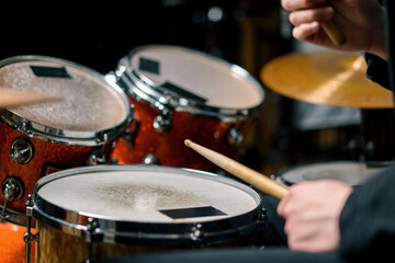 Fototapeta na wymiar drummer plays a drum kit in a recording studio at a professional musician rehearsal recording a song beats the sticks on the instrument close-up