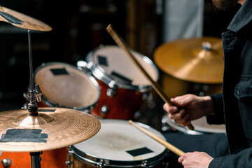 drummer plays a drum kit in a recording studio at a professional musician rehearsal recording a song beats the sticks on the instrument close-up
