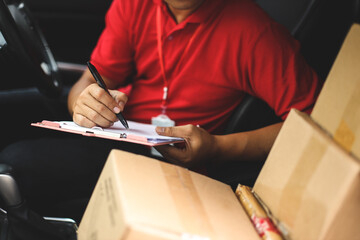 Hand of delivery man checking shipment documents while sitting in driver seat of van. Business cargo express and delivery service concept - obrazy, fototapety, plakaty