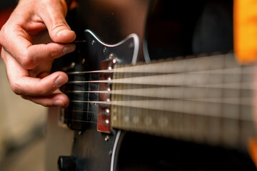 Fototapeta premium rock performer with electric guitar in recording studio recording playing own track creating song musical instrument strings close-up