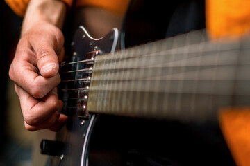 Fototapeta premium rock performer with electric guitar in recording studio recording playing own track creating song musical instrument strings close-up