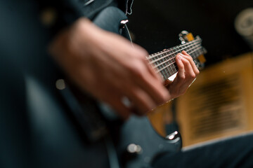 rock performer with electric guitar in recording studio recording playing own track creating song musical instrument strings close-up