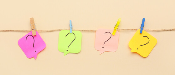 Paper sticks with question marks on rope against beige background
