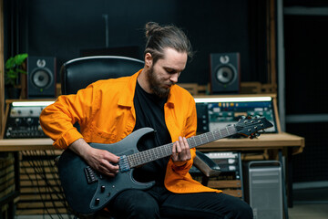 Obraz premium rock performer with electric guitar in recording studio recording playing own track musical instrument strings melody