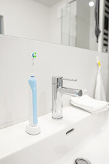 Electric toothbrush on white sink in bathroom