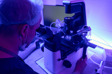 Laboratory technician is adjusting microscope with micromanipulator