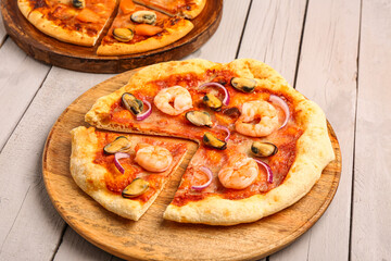 Plate of tasty seafood pizza on light wooden background
