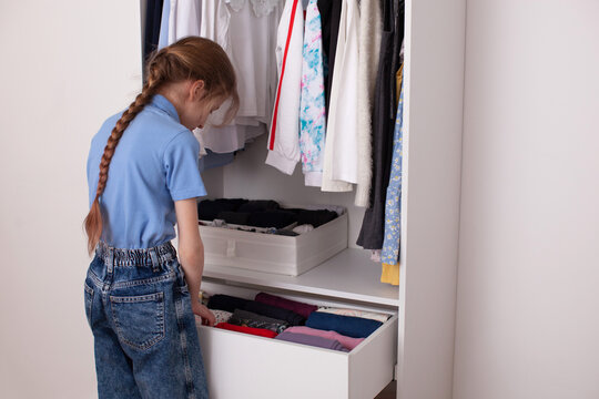 How to organize your wardrobe. Vertical storage of clothing in wardrobe. White closet in kids room. 