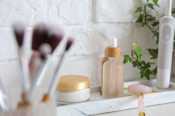 Fototapeta na wymiar Bath accessories with facial massage tool on table near white brick wall