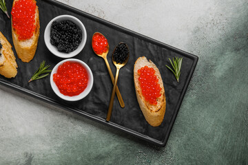 Tasty bruschettas with red and black caviar on color background