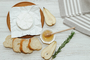 Camembert cheese with pear and rosemary sprig with honey on the table.