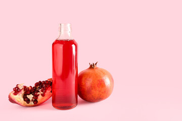 Bottle of fresh pomegranate juice on pink background