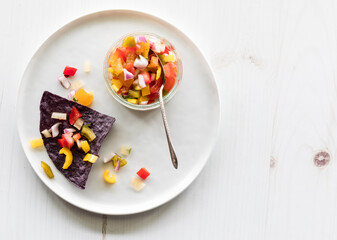 A crispy blue corn tortilla chip topped with homemade chunky salsa.