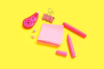 Sticky notes with different stationery supplies on yellow background