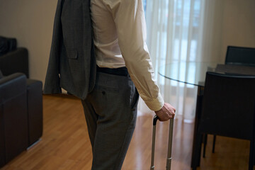 Traveling businessman stands in a hotel room with travel suitcase