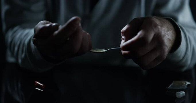 Drugs, hands and syringe, lighter and spoon in studio isolated on a black background. Drug addiction, teaspoon and man with fire, person and junkie cooking dose of heroin, crack or cocaine for crime