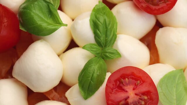 Caprese , rotation in circle. Mozzarella cheese balls, red cherry tomato, yellow tomato and basil leaf, Turning. selective focus.