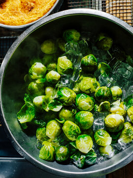 Iced blanched brussels sprouts in a stainless steel bowl