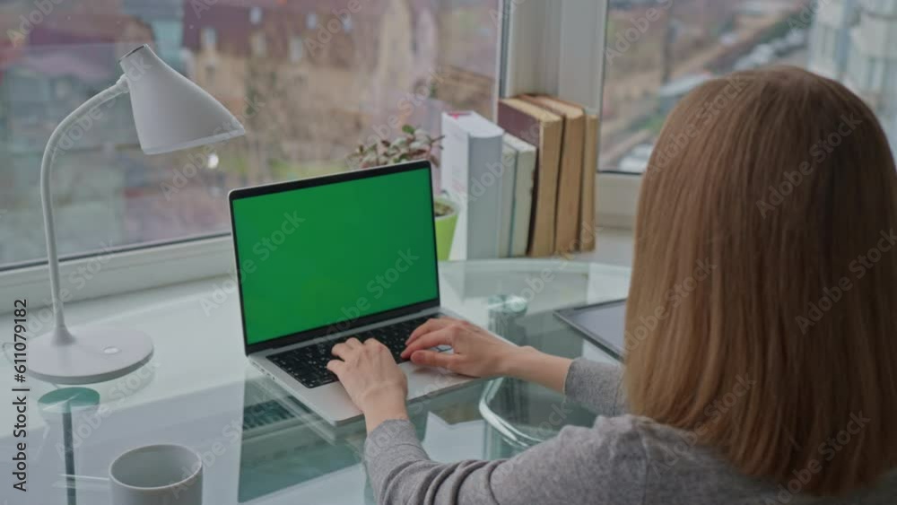 Poster unrecognizable woman sitting at workplace typing on keyboard laptop with green display workspace wit