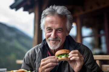 Close-up portrait photography of a satisfied mature man eating burguer against a picturesque mountain chalet background. With generative AI technology