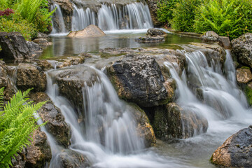 beautiful landscape with waterfall falling from stone wall in japanese style landscape park....