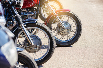 Obraz premium Motorcycle front wheels close-up. Motorcycles stand in a row on the sidewalk, side view. Motorcycles are parked in the motorcycle parking area.