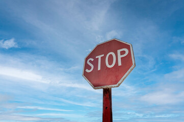 Red octagonal stop sign against a blue sky background.