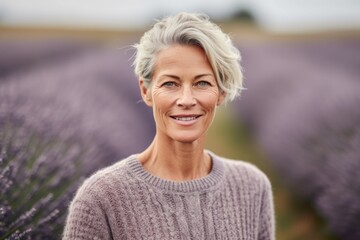 Headshot portrait photography of a satisfied mature woman wearing a cozy sweater against a lavender field background. With generative AI technology