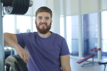 Bearded young man training in the gym and looking at camera 