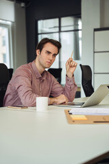 Serious company employee pondering over job task in his workplace