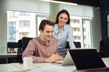 Pleased corporate worker showing his task performance to female colleague