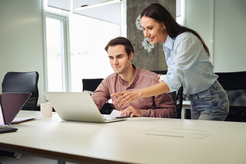 Friendly office worker explaining something to her new coworker